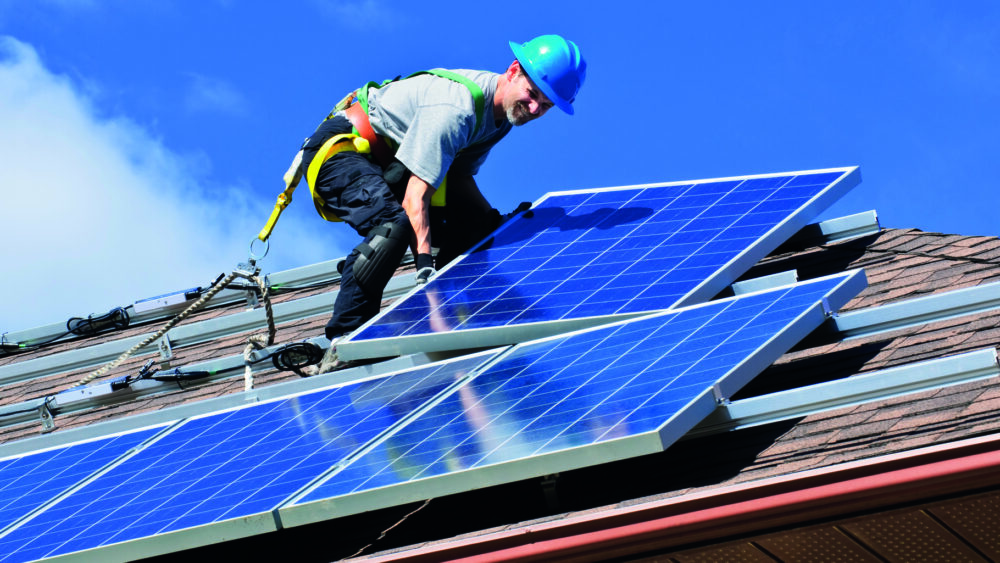 Homme sur un toit en train de poser des panneaux solaires